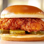 A side-by-side comparison of fried chicken from Popeyes, KFC, and Chick-fil-A, showing crispy textures and golden-brown coating.